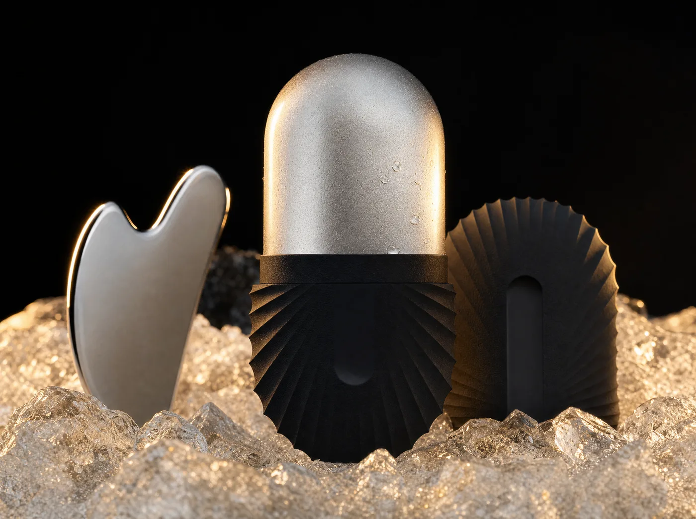 A stainless ice roller with a black handle resting in crushed ice