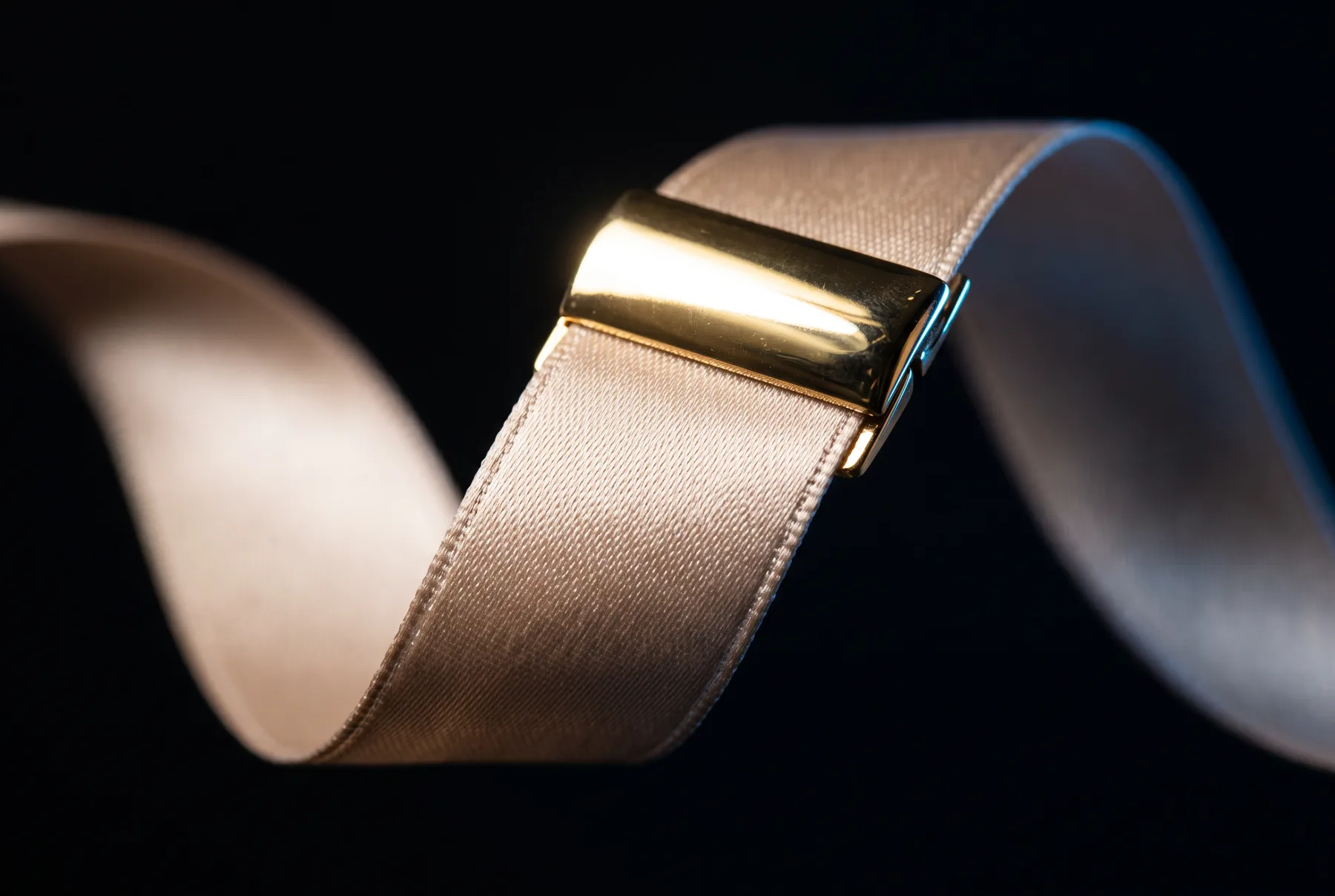 Macro detail of the champagne satin weave and the polished gold clasp